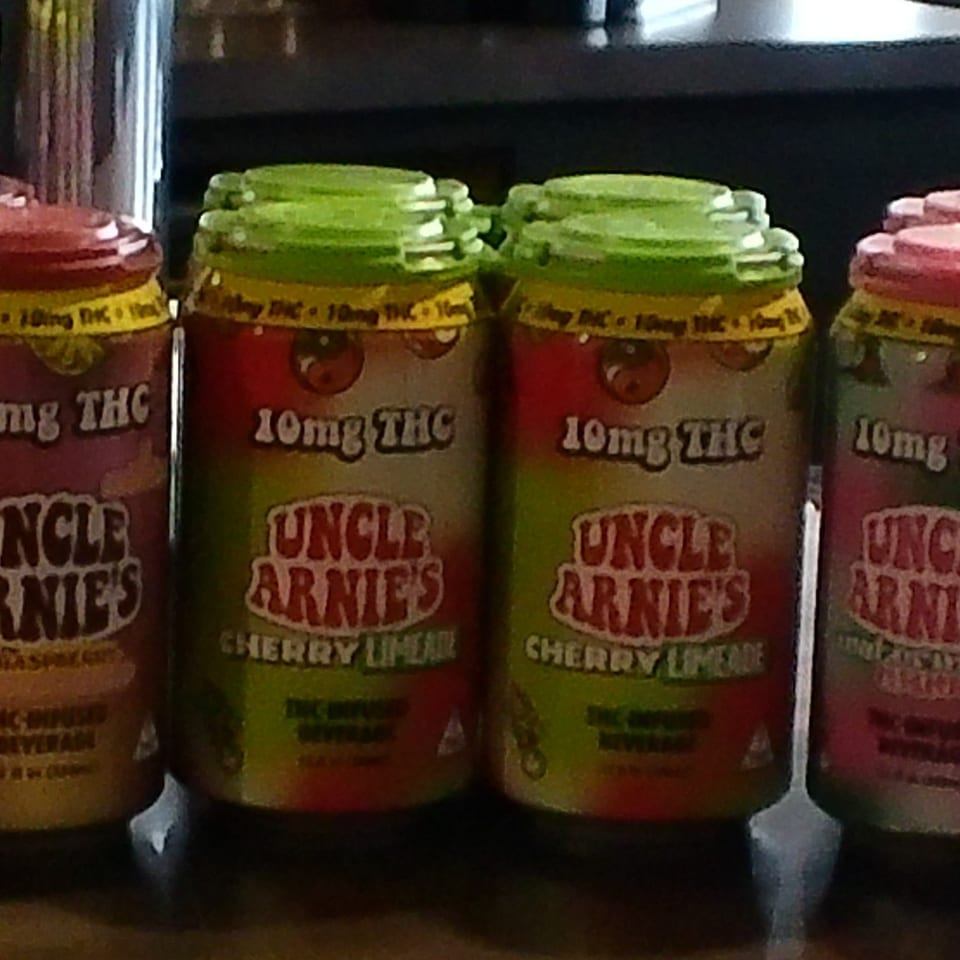 Several cans of "Uncle Arnie's" cherry limeade and raspberry THC-infused beverages on display.